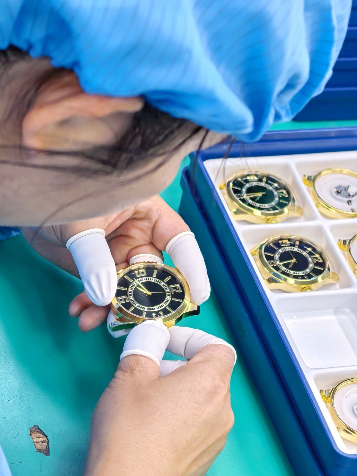 Technician inspecting a gold-tone watch during final quality control.