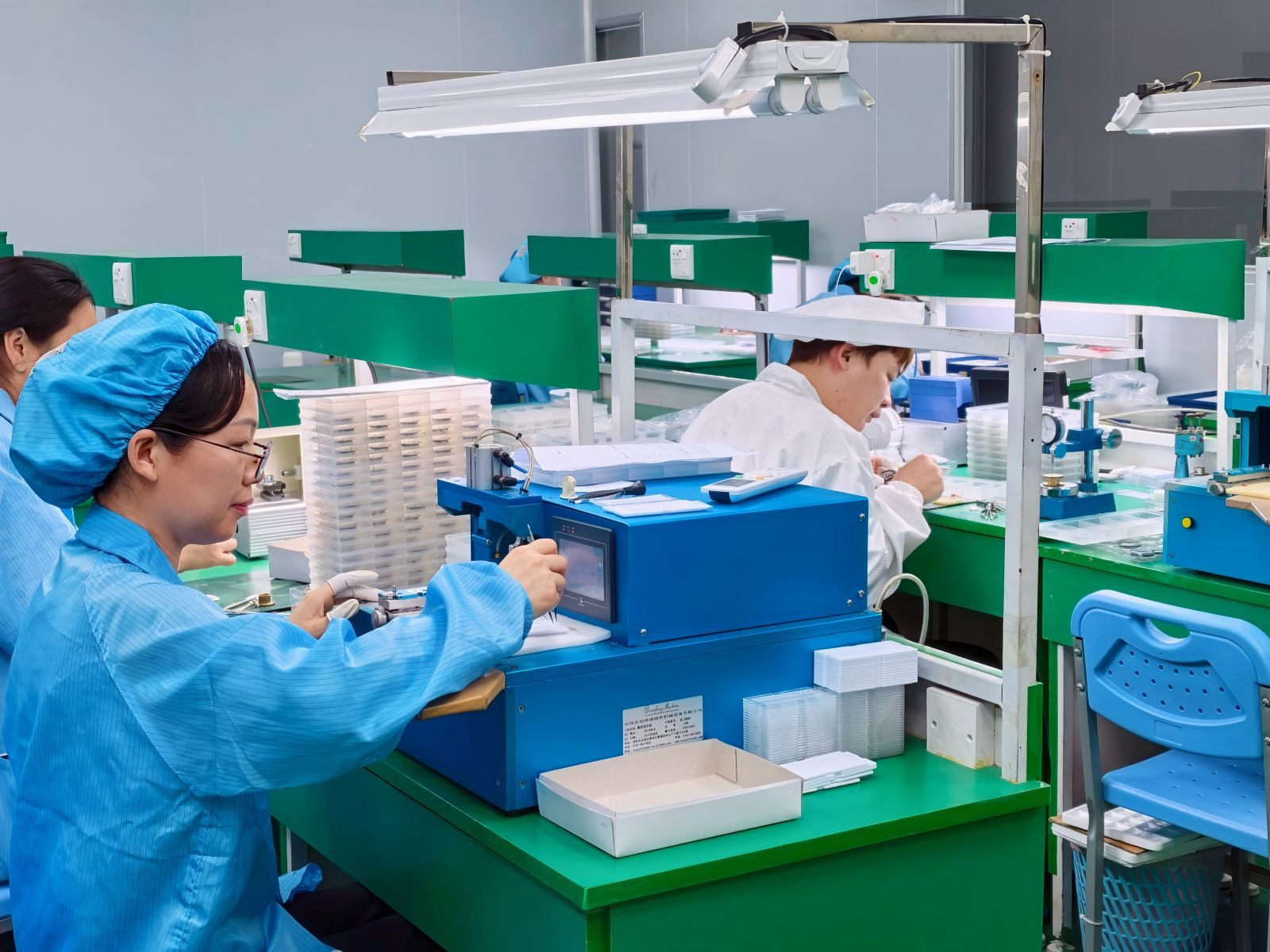 Watch production workshop view showing operator benches and trays.